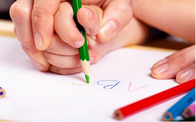 Hướng dẫn bé cách cầm bút đúng cách. (Ảnh: vn.theasianparent.com)