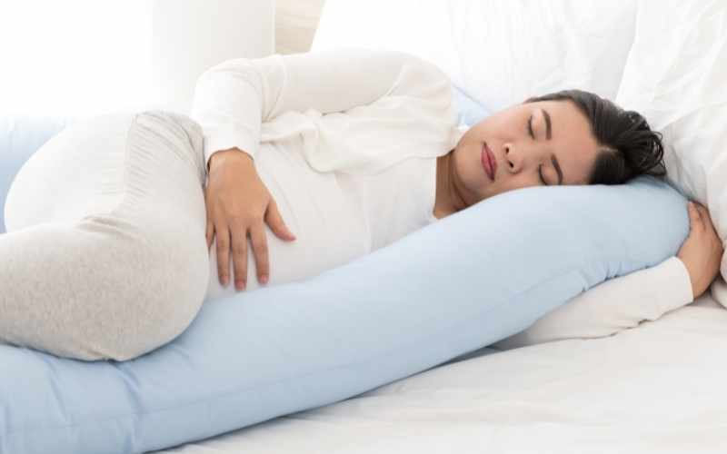 Nằm nghiêng sang bên trái và kê gối giúp mẹ giảm bớt chứng đau xương mu. (Ảnh: Sưu tầm Internet)