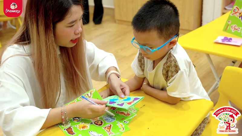 Các cô hướng dẫn bé cách làm thiệp 20/10 trong trang trí & hoàn thiện. (Ảnh: Monkey)